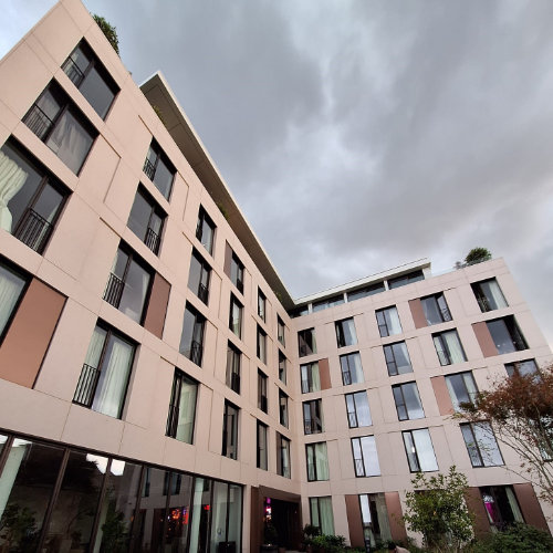 External facade of Hazel Court featuring Moleanos-look porcelain cladding, bronze decorative stainless steel panels, and a modern entrance. Completed project showcasing a sophisticated blend of materials.