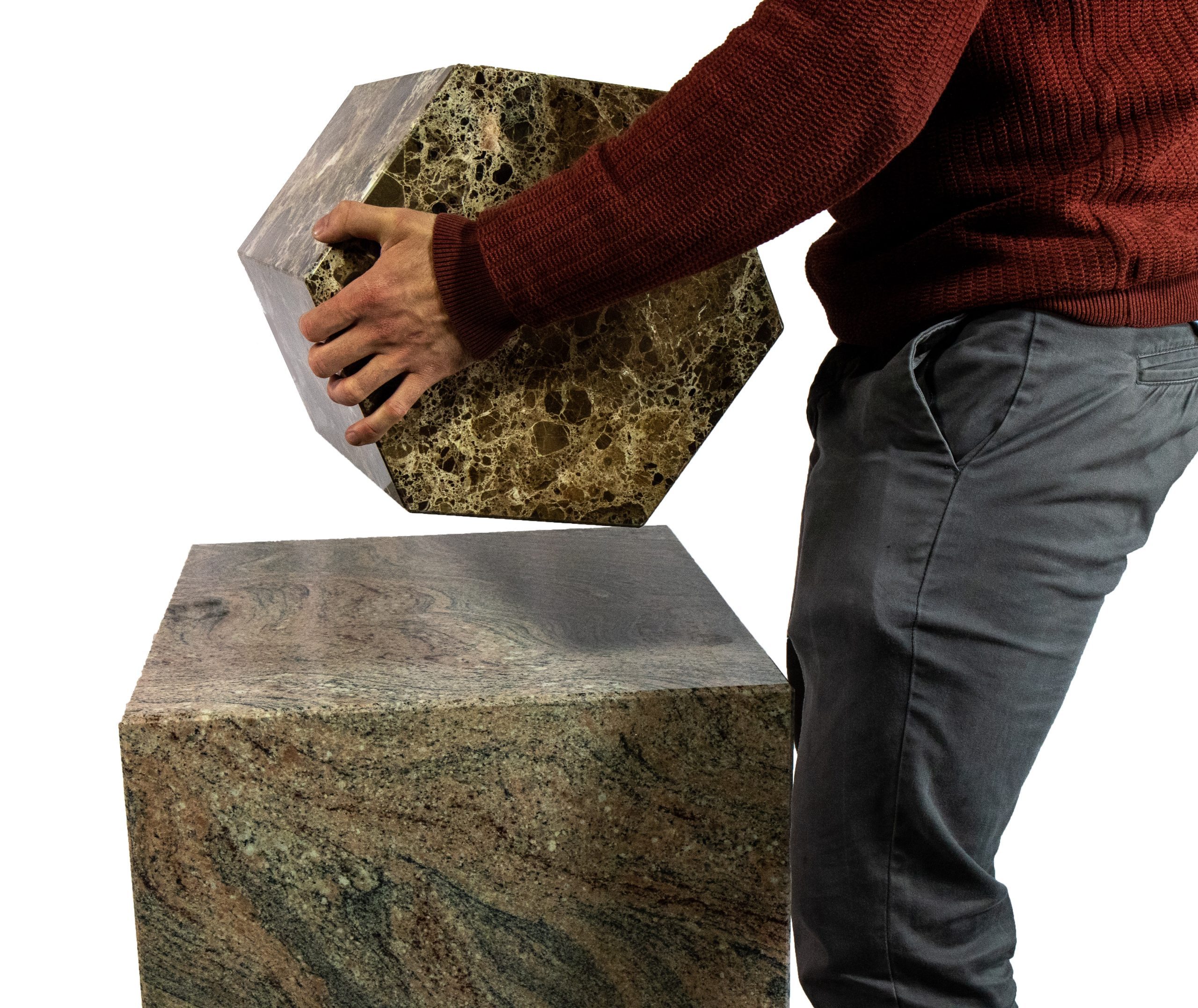 Person lifting a lightweight stone fabricated hexagonal plinth, highlighting its lightweight design.