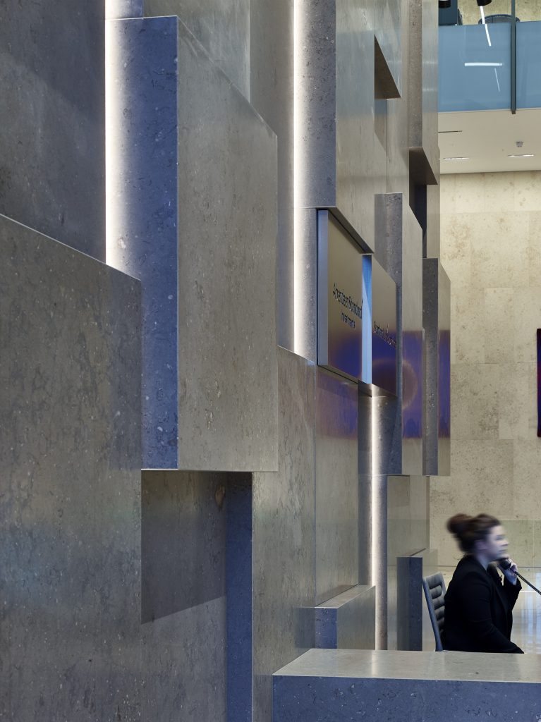 Close-up of Standard Life Edinburgh internal lightweight stone cladding featuring side-lit monolithic stone block elements across the facade.