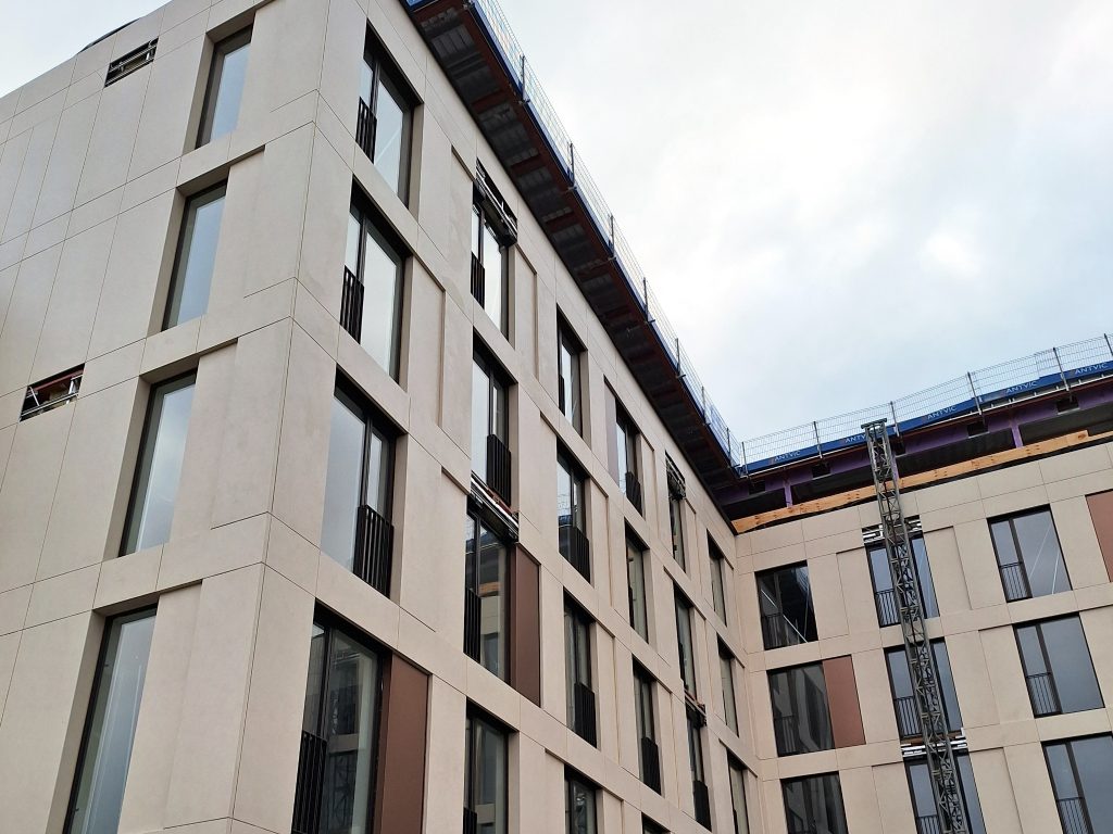 Hazel Court project with porcelain facade panels, bronze steel decorative panels, windows, and construction elements midway through installation.