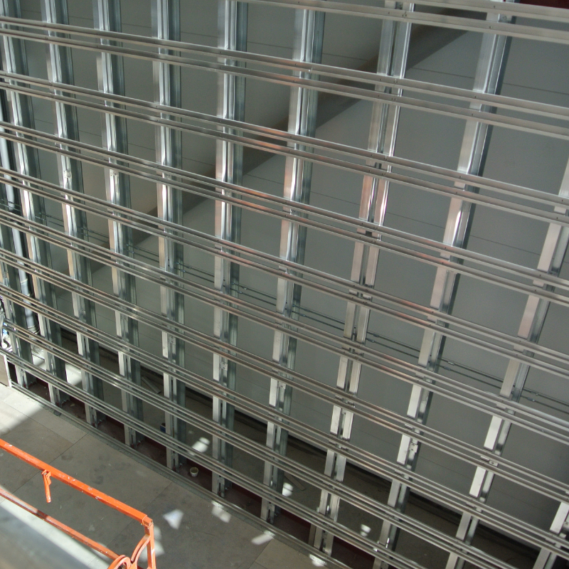 Image of a lightweight aluminium subframe system for an internal lightweight cladding facade, showing a grid-like framework with vertical and horizontal rails supporting cladding panels.