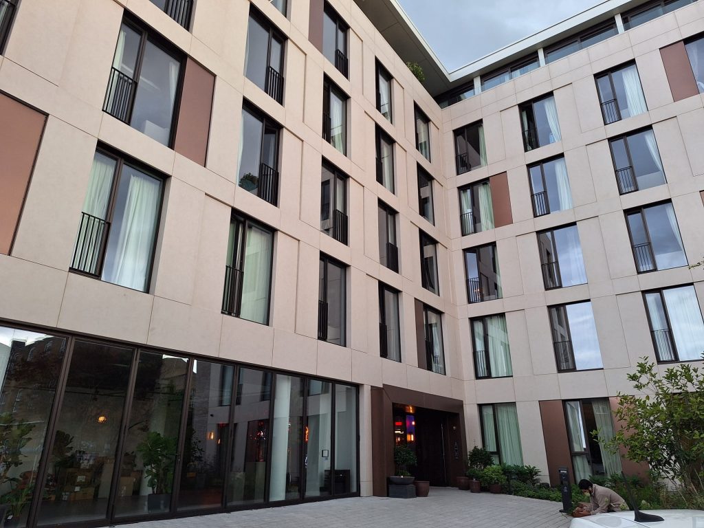 External facade of Hazel Court featuring Moleanos-look porcelain cladding, bronze decorative stainless steel panels, and a modern entrance. Completed project showcasing a sophisticated blend of materials.