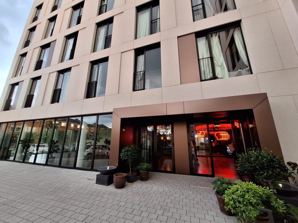 External facade of Hazel Court featuring Moleanos-look porcelain cladding, bronze decorative stainless steel panels, and a modern entrance. Completed project showcasing a sophisticated blend of materials.