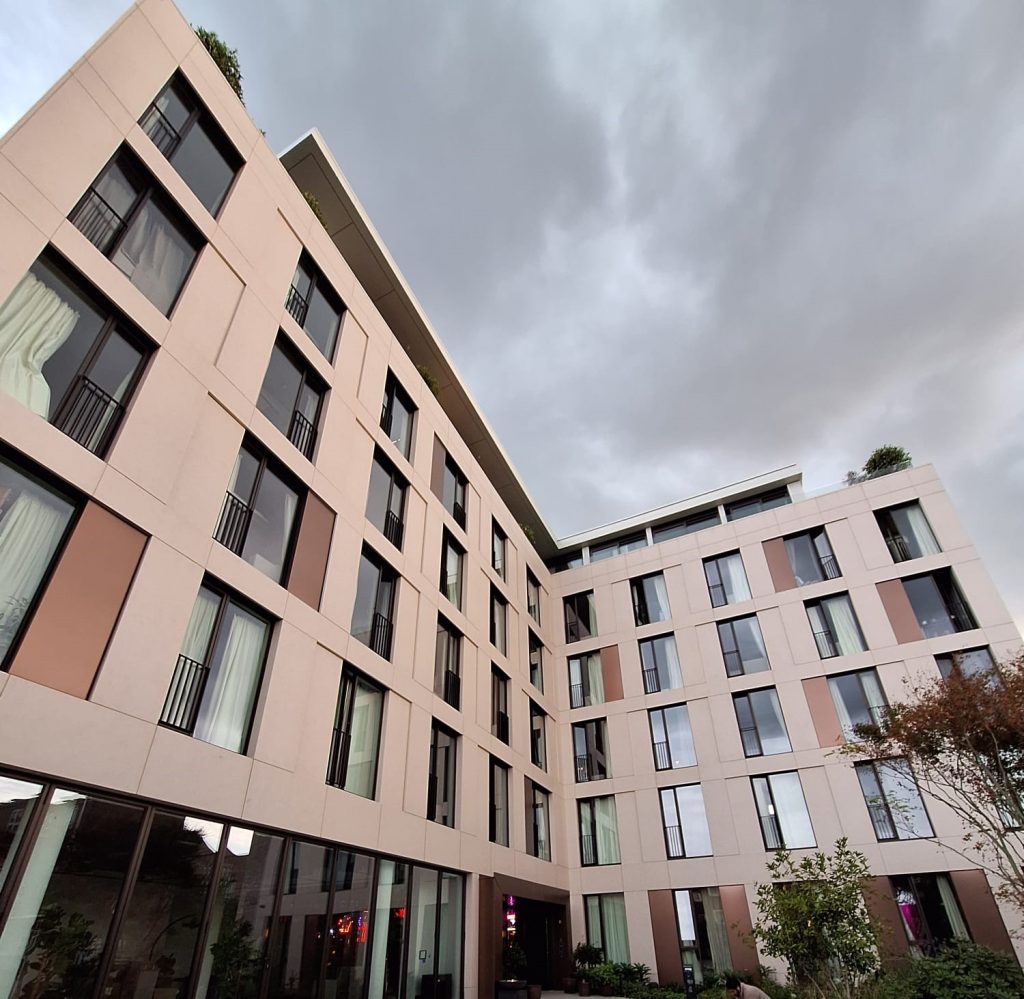 External facade of Hazel Court featuring Moleanos-look porcelain cladding, bronze decorative stainless steel panels, and a modern entrance. Completed project showcasing a sophisticated blend of materials.